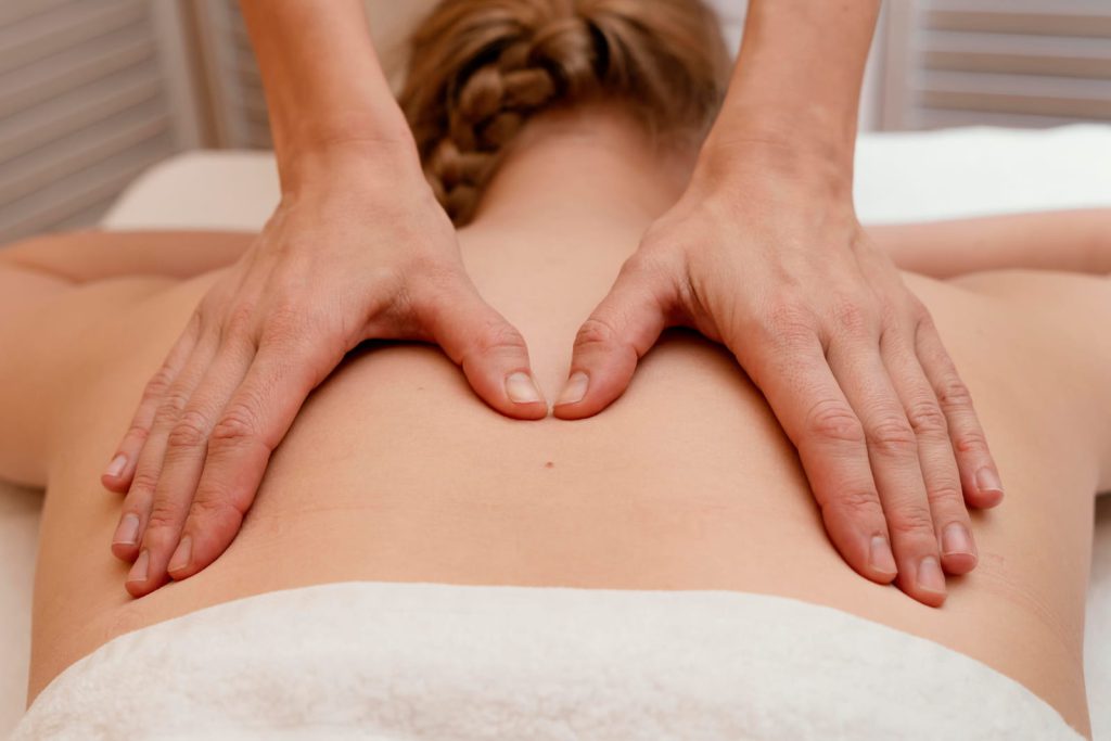 Therapist's hands working on the shoulders and upper back of a client